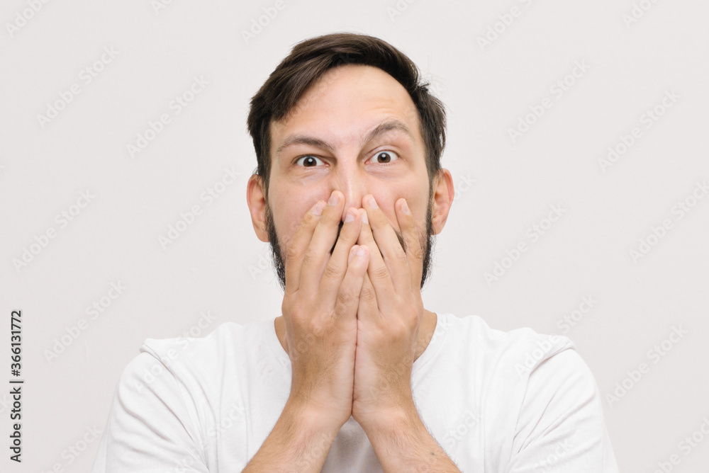 close portrait. young man covers his mouth with his palms close portrait. young man covers his mouth with his palms
