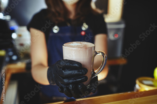 Barista wearing medical latex black gloves  making pink matcha latte with milk.Bartender preparing tasty drink.Blurred image selective focus