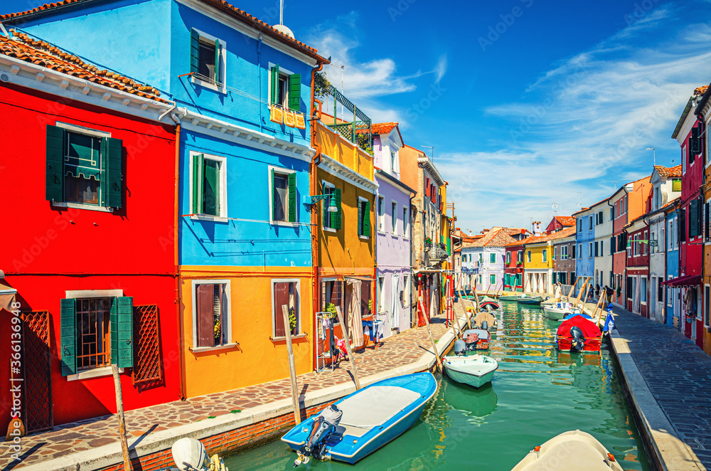 Colorful houses of Burano island. Multicolored buildings on fondamenta embankment of narrow water canal with fishing boats in sunny day, Venice Province, Veneto Region, Northern Italy. Burano postcard