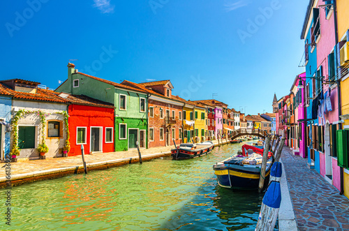 Colorful houses of Burano island. Multicolored buildings on fondamenta embankment of narrow water canal with fishing boats and wooden bridge, Venice Province, Veneto Region, Northern Italy