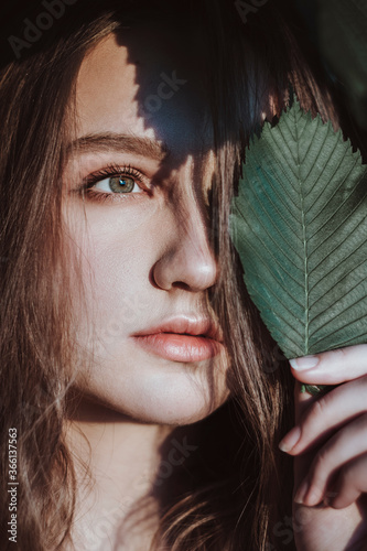 portrait of a woman with a leaf near her face
