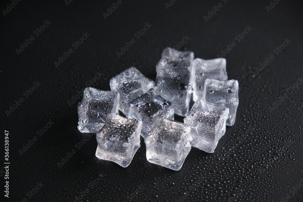 Ice cubes on a reflecting table with drops of water on a black background Ice cubes on a reflecting table with drops of water on a black background