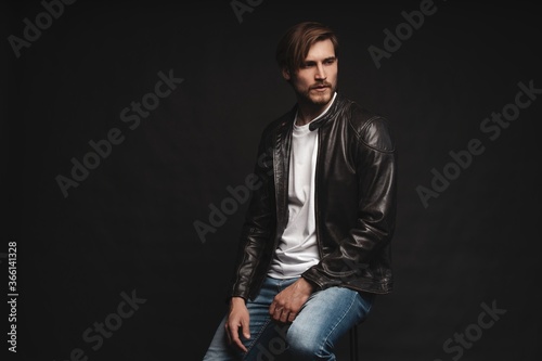 Fashion man, Handsome serious beauty male model portrait wear leather jacket, young guy over black background