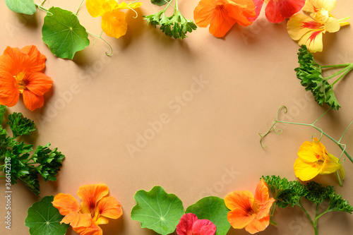 Edible nasturtium flowers and fresh greens on natural beige. Top view. Space for text. Trendy food decor.