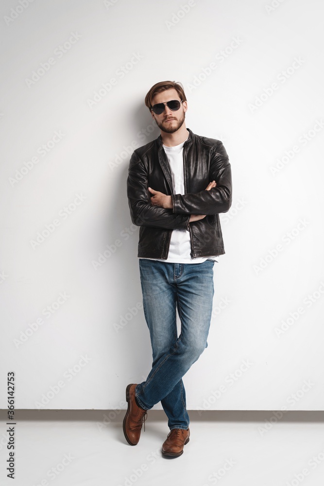 Fashion man, Handsome serious beauty male model portrait wear sunglasses and leather jacket, young guy over white background Fashion man, Handsome serious beauty male model portrait wear sunglasses and leather jacket, young guy over white background