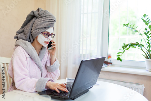 Woman applying facial clay mask. The young woman is working remotely. Concept of the workplace at home, working remotely. Creative.
