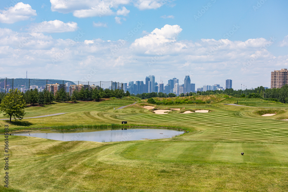 green golf court with a city in the background in summer