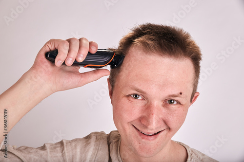 Man doing haircut by himself at home while Covid-19 quarantine. Self isolation lifestyle.