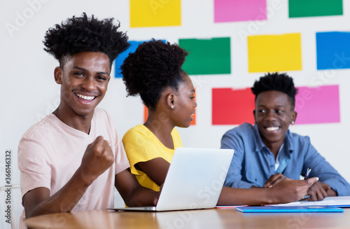 Successful african american male student at computer with group of students