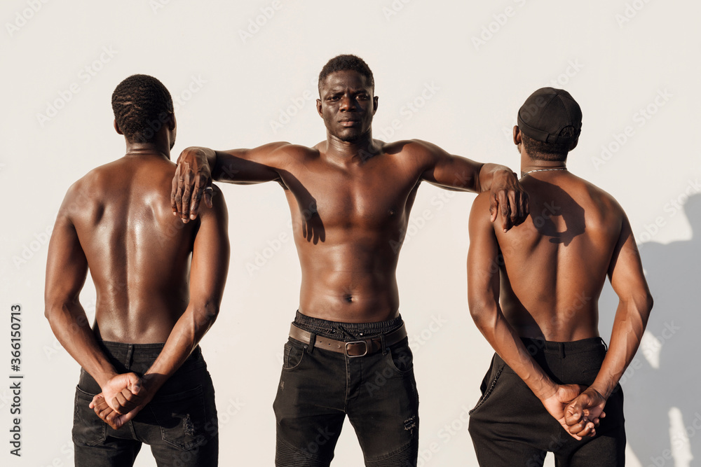 Black man leaning on friends, crossing hands behind their backs Black man leaning on friends, crossing hands behind their backs