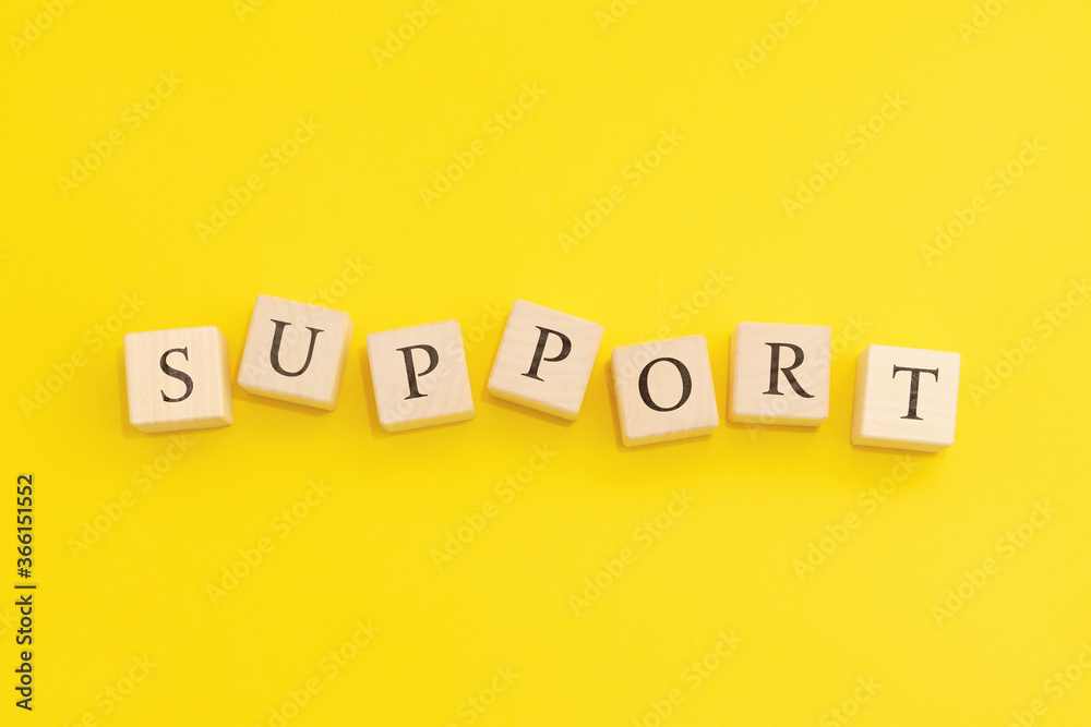 The word Support is made of wooden cubes on a yellow background. The word Support is made of wooden cubes on a yellow background.