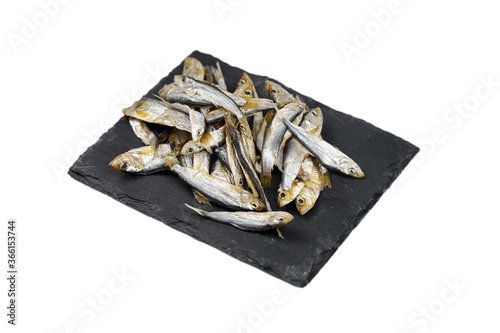 Small dried fish on slate board isolated on white background