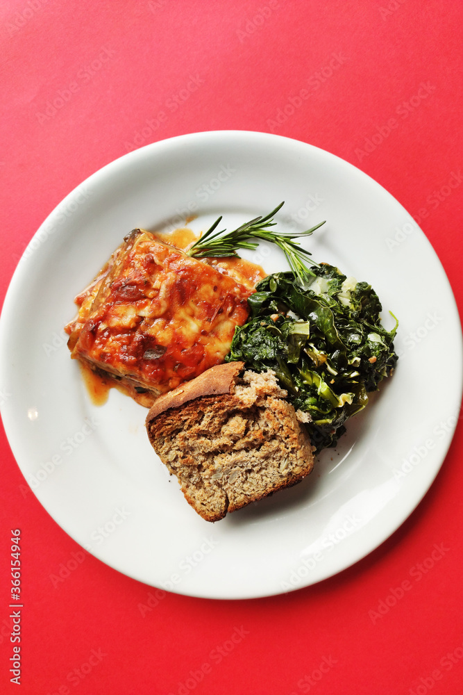 Lasagna dish with breag and vegetables and red background