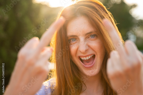 Portrait of laughing redheaded woman giving the finger