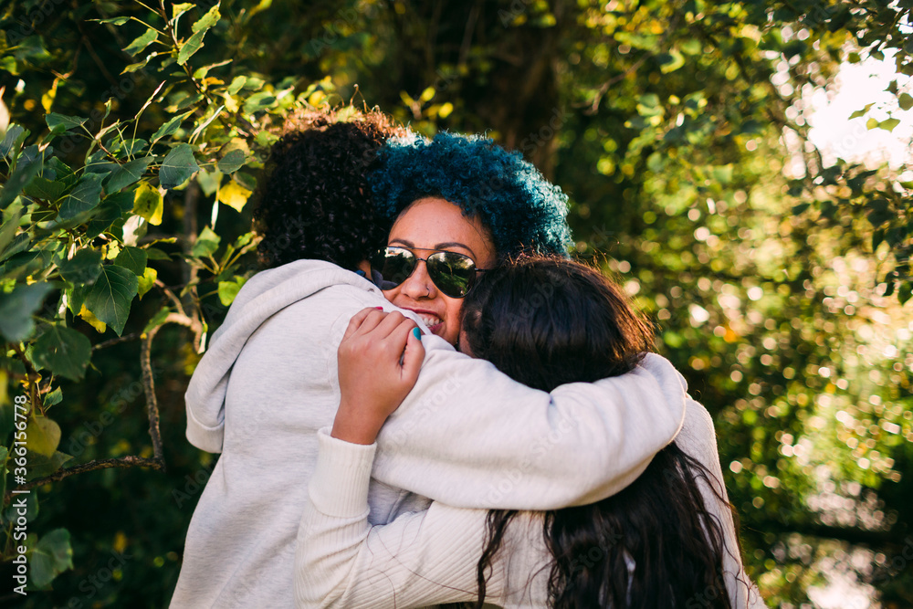 Loving children embracing mother with blue hair against trees in park Loving children embracing mother with blue hair against trees in park