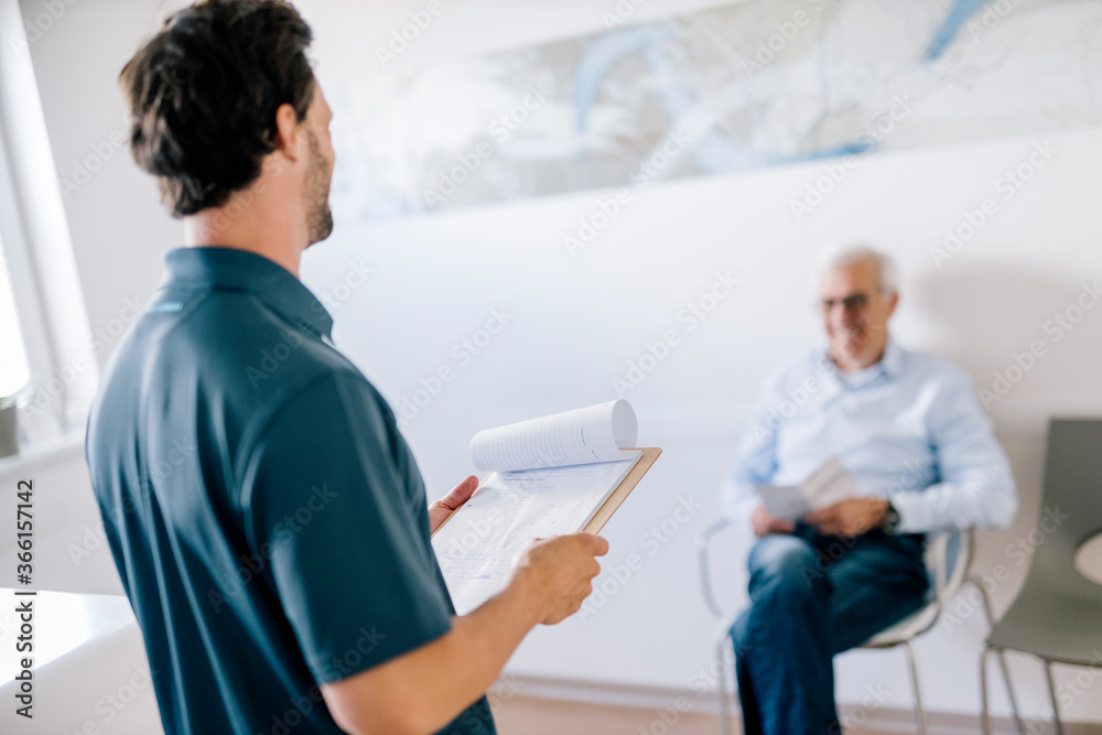 Physiotherapist with patient's record meeting patient at the reception Physiotherapist with patient's record meeting patient at the reception
