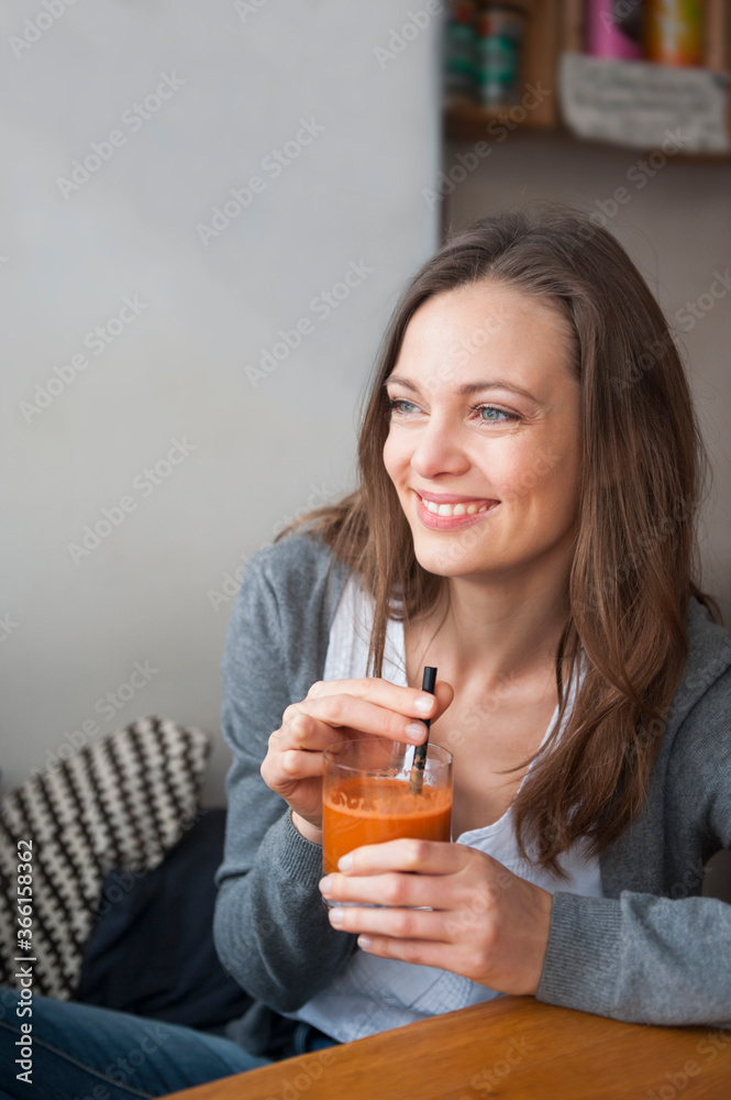 Portrait of smiling woman drinking smoothie in a coffee shop looking at distance Portrait of smiling woman drinking smoothie in a coffee shop looking at distance