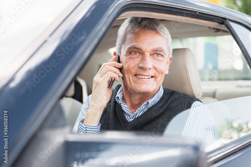 Portrait of smiling senior businessman on the phone in car