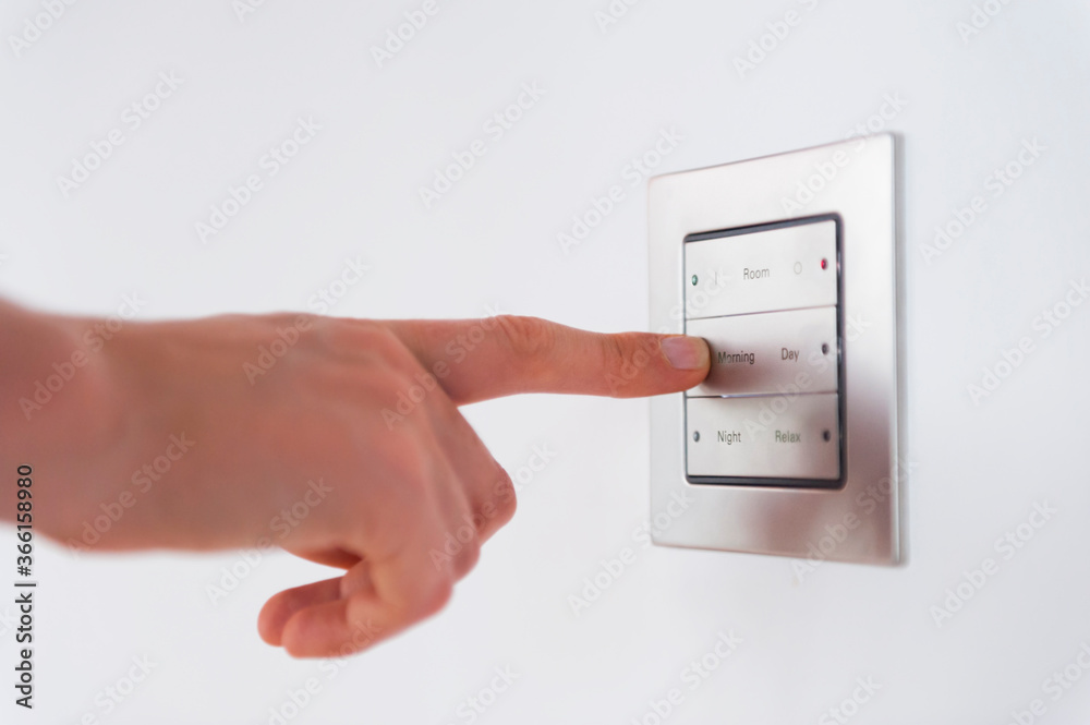 Cropped hand of woman pressing push button on wall at home Cropped hand of woman pressing push button on wall at home