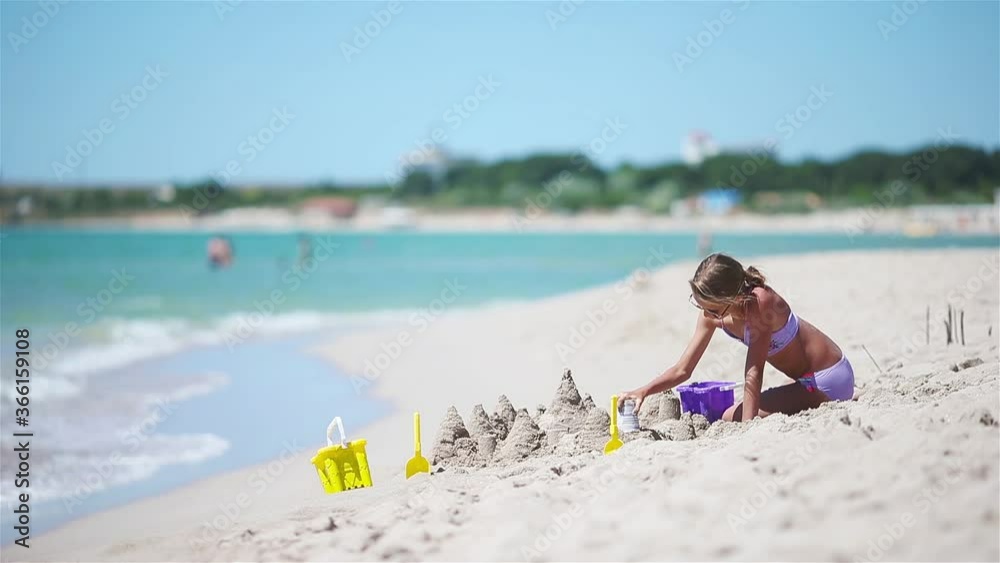 Little girl at tropical white beach making sand castle Little girl at tropical white beach making sand castle