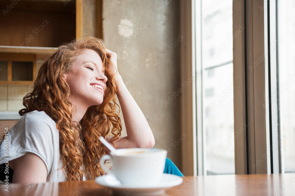 Happy young woman with hand in hair sitting at home Happy young woman with hand in hair sitting at home