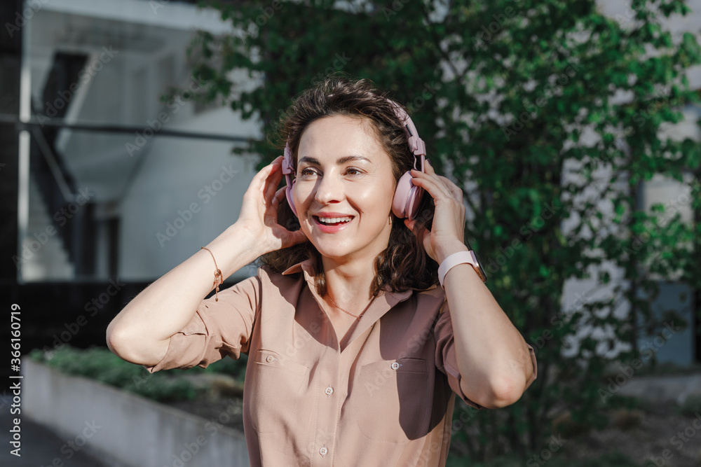 Happy businesswoman wearing headphones during sunny day