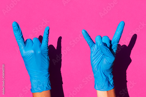 Hands of woman wearing latex gloves making sign of horns photo