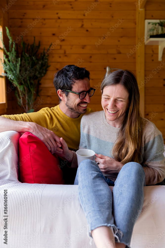 Cheerful couple holding hands while relaxing on sofa in log cabin Cheerful couple holding hands while relaxing on sofa in log cabin