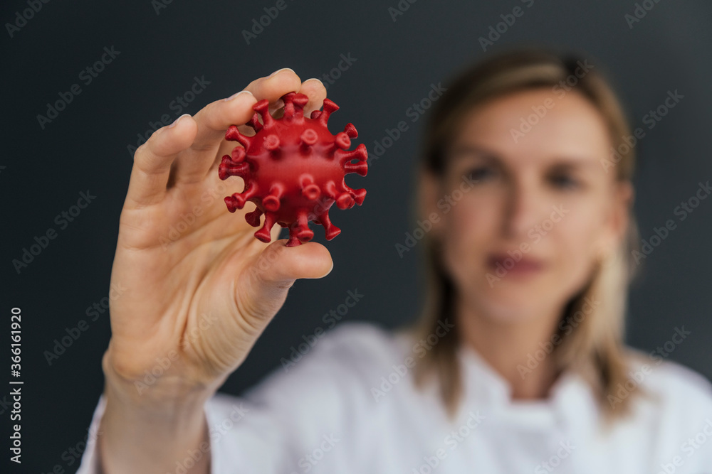 Hand of female scientist holding 3D model of SARS-CoV-2 virus, close-up Hand of female scientist holding 3D model of SARS-CoV-2 virus, close-up