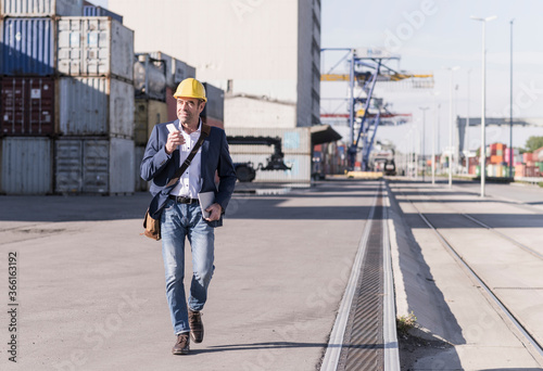 Wallpaper Mural Businessman with smartphone and digital tablet walking in front of cargo containers Torontodigital.ca