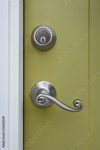 Photograph of a front door to a home with a fancy pewter door knob and deadbolt set