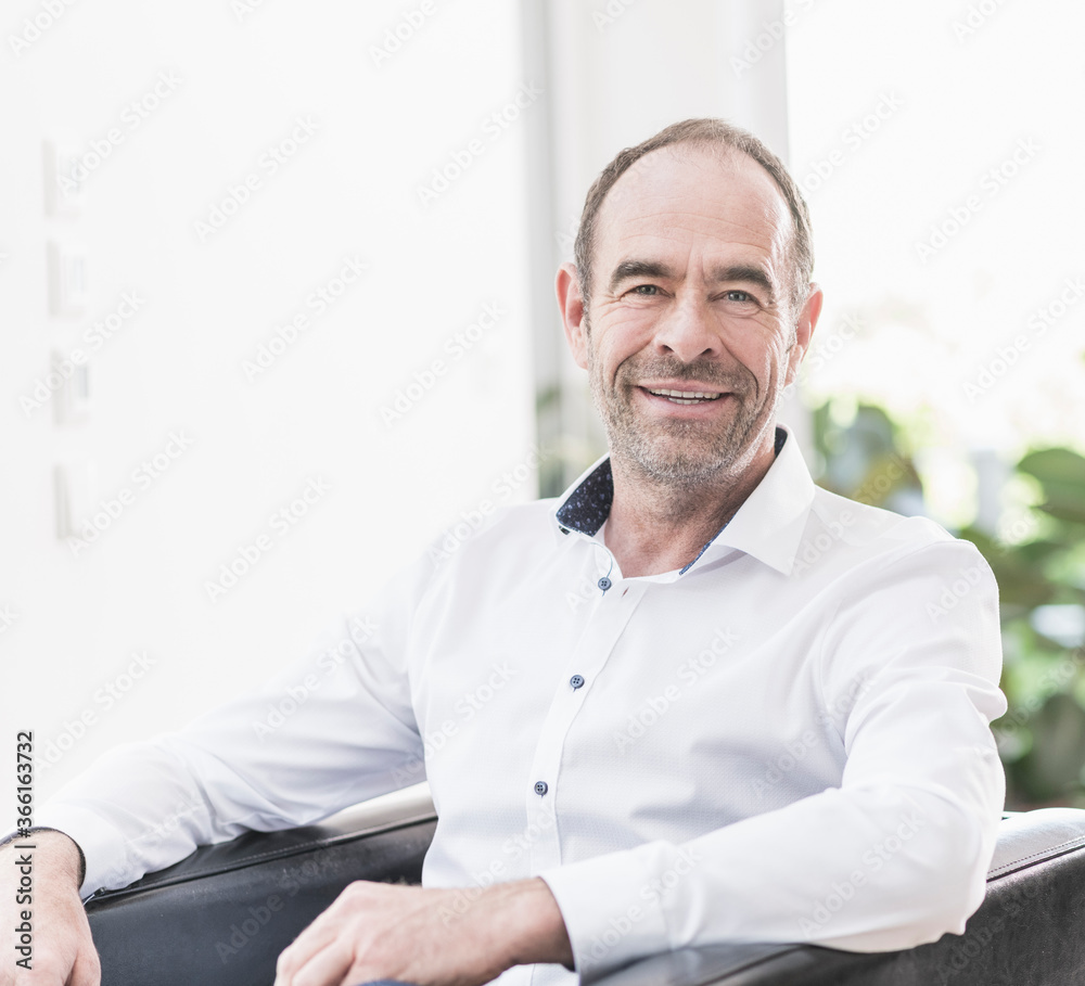 Portrait of smiling mature man sitting in armchair Portrait of smiling mature man sitting in armchair