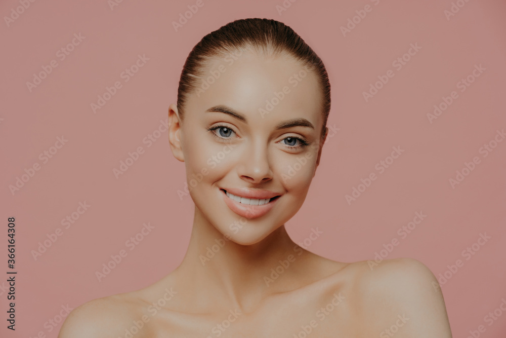 Shirtless beautiful young female model with makeup and clean fresh skin, cares about complexion, smiles gently and looks directly at camera, isolated. Cosmetology, spa, facial treatment concept Shirtless beautiful young female model with makeup and clean fresh skin, cares about complexion, smiles gently and looks directly at camera, isolated. Cosmetology, spa, facial treatment concept