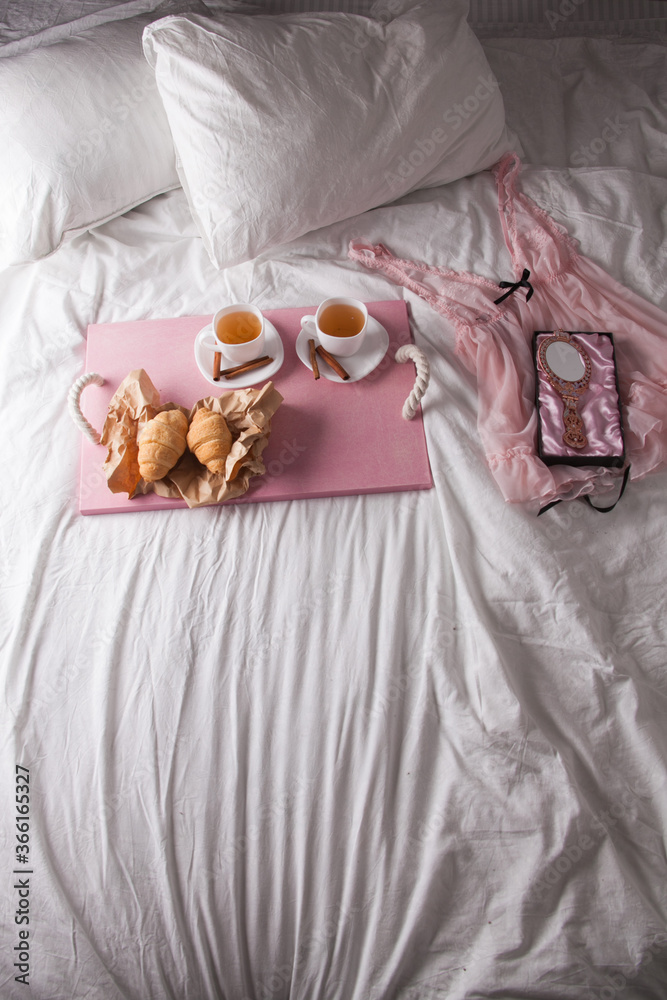 breakfast in bed with fruits and pastries on a tray -waffles, croissants, coffe and juice