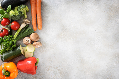 Colorful organic vegetables on the side of a light gray surface with large copy space, healthy kitchen background, high angle view from above