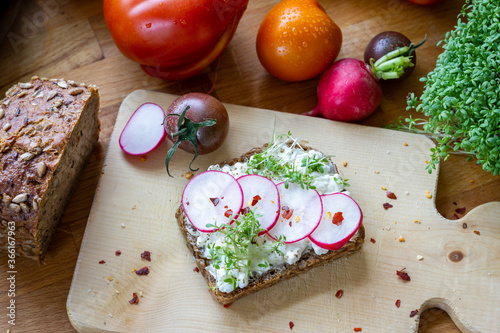 Vollkornbrot mit Frischkäseaufstrich und Garnierung aus Radieschen Kresse und tomaten