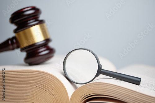 Judicial case investigation concept. The magnifying glass on the book next to the judge hammer. photo