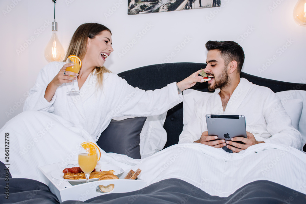 woman feeding her partner while having breakfast in bed woman feeding her partner while having breakfast in bed