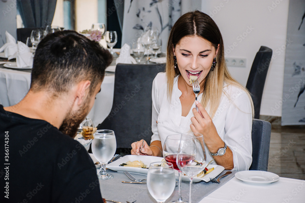 woman excited about the food she is eating on a date in a restaurant with her partner woman excited about the food she is eating on a date in a restaurant with her partner