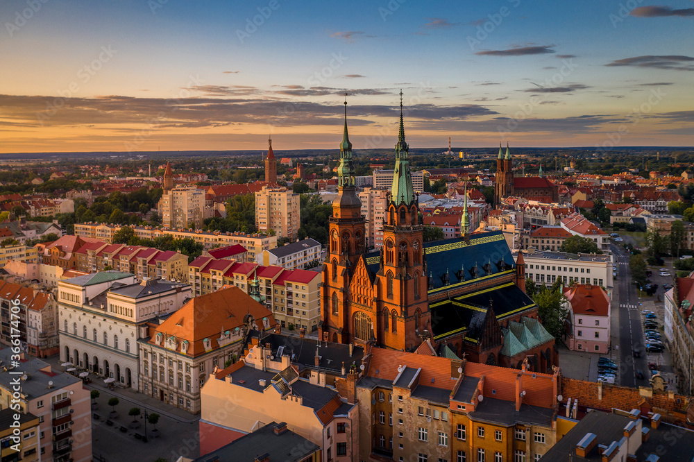 Aerial drone view of the Cathedral of St. Peter and Paul the Apostles and old town buildings before sunset. The sun's rays beautifully highlight the urban architecture in Legnica, Poland