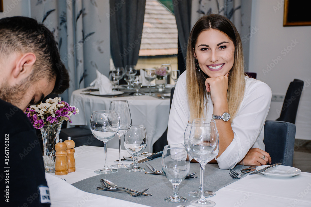 Woman smiling while her partner is looking down picking what they are going to eat Woman smiling while her partner is looking down picking what they are going to eat