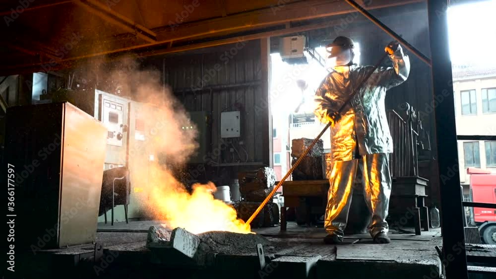 Metallurgist Job Worker In A Steel Plant Hot Molten Metal Pouring. Heavy Industry Worker Working Hard. 
molten iron 