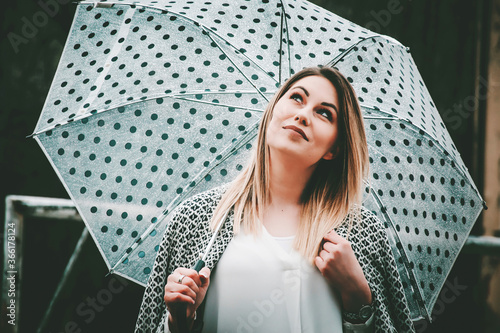 Joyful woman holding her umbrella and daydreaming while outside