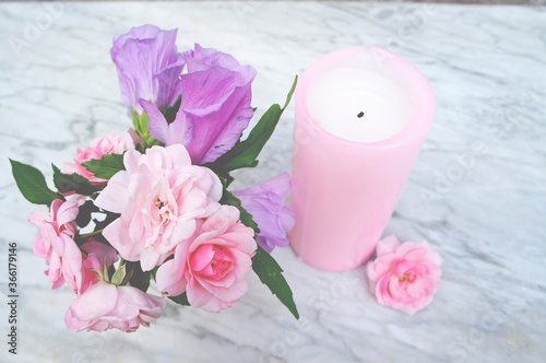 candle and rose petals on marble background.