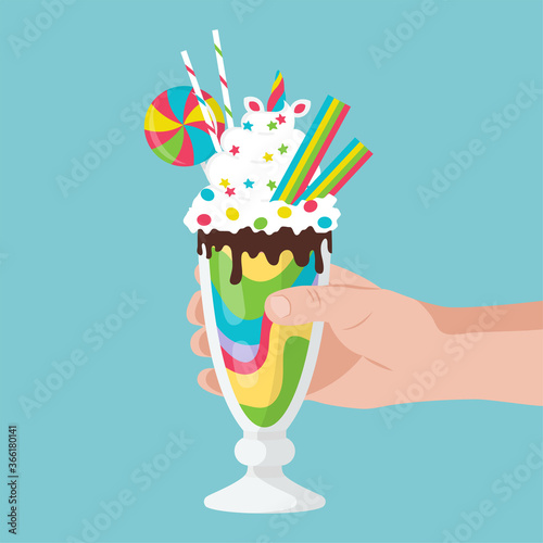 Hand holds a Rainbow milkshake with unicorn.