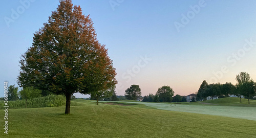 early foggy sunrise on golf course pond leaves changing color
