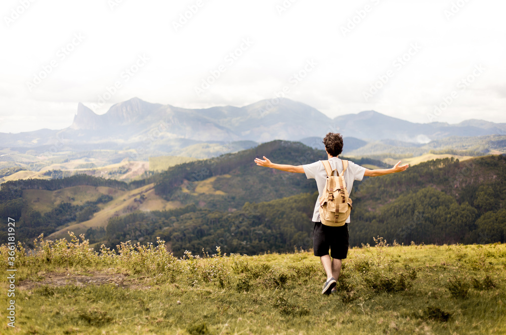 young adventurous traveler with arms raised on top of a mountain carrying a backpack and admiring the mountains of the State of Espirito Santo, Brazil. young adventurous traveler with arms raised on top of a mountain carrying a backpack and admiring the mountains of the State of Espirito Santo, Brazil.