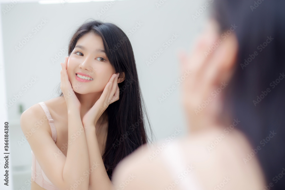 Beautiful young asian woman smiling look at mirror of checking face with skin care and cosmetic for rejuvenation and hygiene, beauty girl happy clean facial with cream or lotion and for health. Beautiful young asian woman smiling look at mirror of checking face with skin care and cosmetic for rejuvenation and hygiene, beauty girl happy clean facial with cream or lotion and for health.