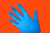 Hand in blue medical glove isolated on orange with gesture. Protection concept