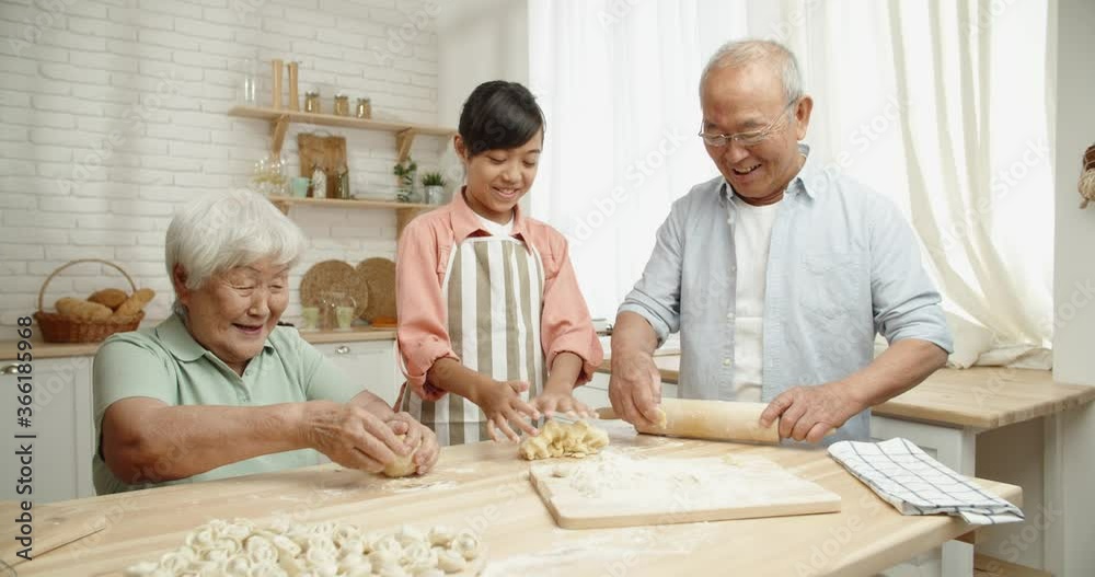 Senior asian couple teaching their teen granddaughter how to prepare dough for dumplings, spending time together - childhood memories, family ties concept 4k footage Senior asian couple teaching their teen granddaughter how to prepare dough for dumplings, spending time together - childhood memories, family ties concept 4k footage